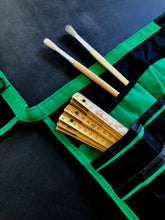 green and black bucket organizer shown flat with paint brushed and old fashion tape measure against black background