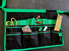 green and black bucket organizer shown flat with hobbies accessories for sewing