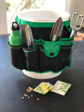 green and black bucket organizer with seeds, garden tool, green water bottle