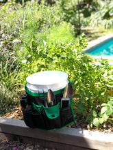 green and black bucket organizer around a white bucket, garden and pool in background
